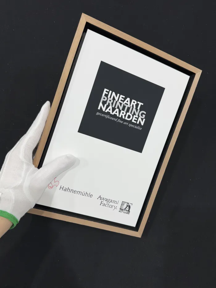 Fine art print in houten baklijst vastgehouden met witte handschoenen.